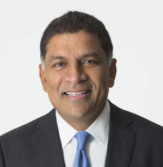 a man wearing a suit and tie smiling at the camera
