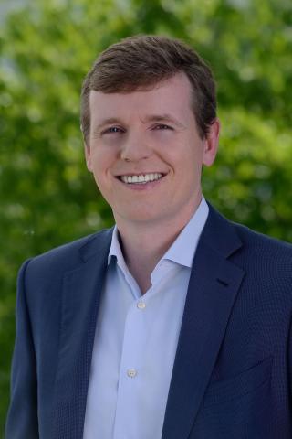 a man wearing a suit and tie smiling at the camera