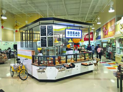 At Lowes Foods in North Carolina, grocery design firm api(+) created a bakery department kiosk called Bread Crumb. It is designed to be a free-floating service area that gives customers the feeling that they are in a self-service bakery. But the kiosk is full-service, with bagged bread on the outside of the kiosk. Employees will slice or help select breads for customers.