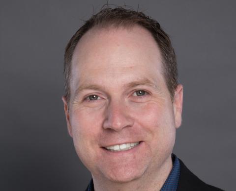a man wearing a suit and tie smiling at the camera