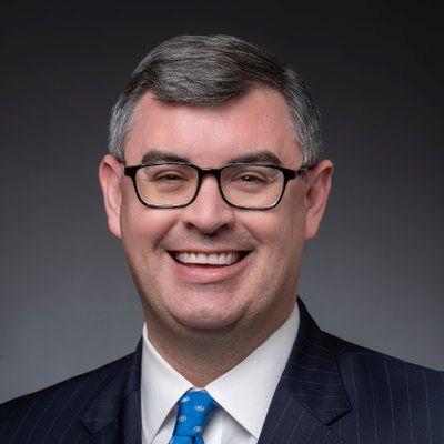 a man wearing a suit and tie smiling at the camera