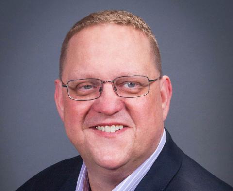 a man wearing glasses and smiling at the camera
