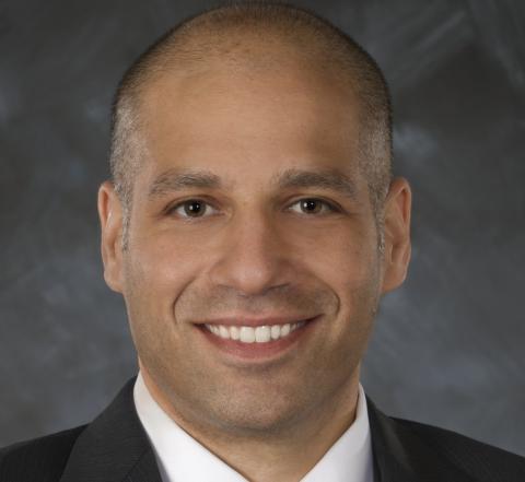 a man wearing a suit and tie smiling and looking at the camera