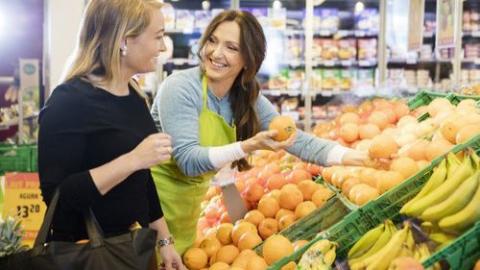 a person standing in front of a store filled with lots of fresh produce