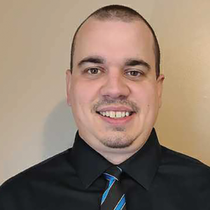 a man wearing a suit and tie smiling at the camera