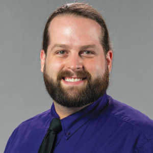 a man wearing a blue shirt and smiling at the camera