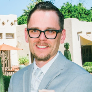 a man wearing glasses and smiling at the camera