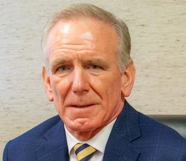 a man wearing a suit and tie smiling at the camera