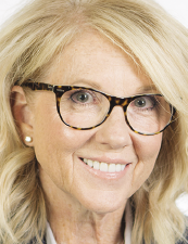 a woman wearing glasses and smiling at the camera