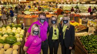 a group of people standing in a store filled with lots of produce