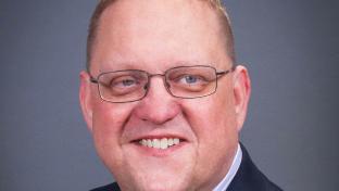 a man wearing glasses and smiling at the camera