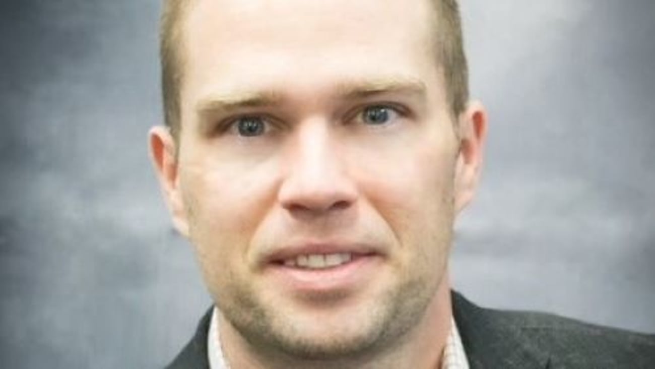 a man wearing a suit and tie smiling at the camera