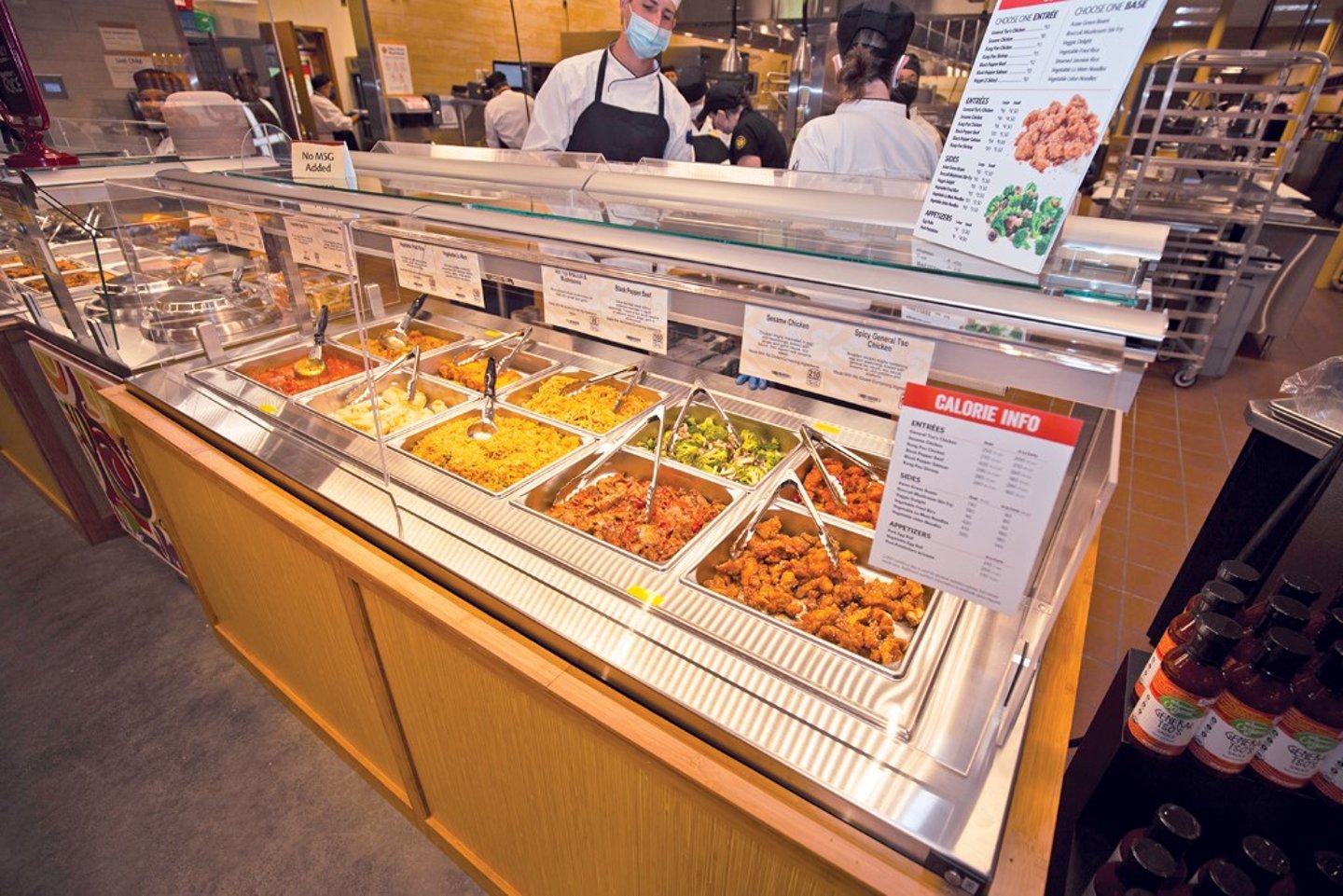 The company has, for now, moved its self-service hot bars to the perimeter, encased them in plexiglass and made them full-service, with plenty of associates on hand to serve Asian stir-fries and Buffalo chicken wings to customers. 