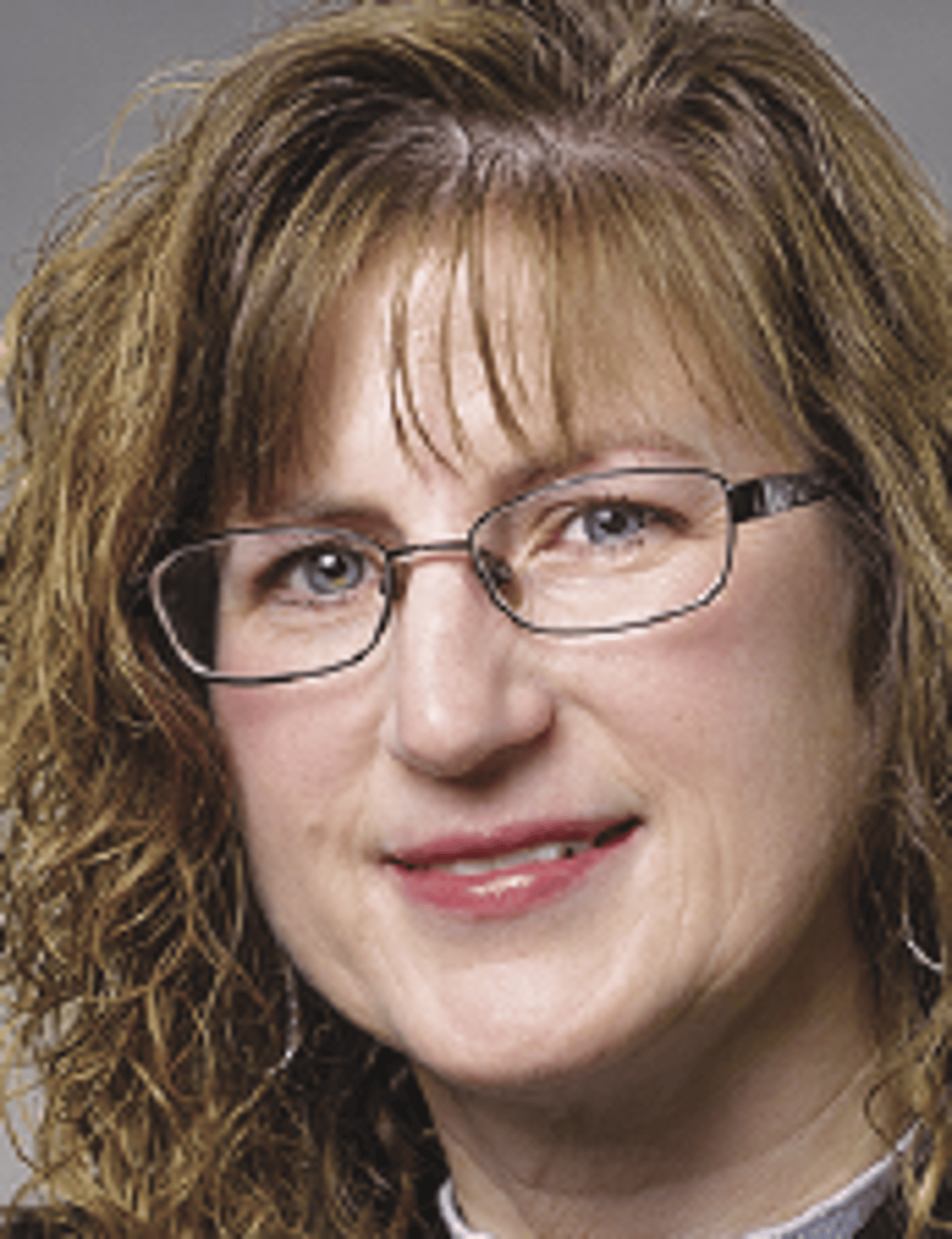 a close up of a woman wearing glasses and smiling at the camera