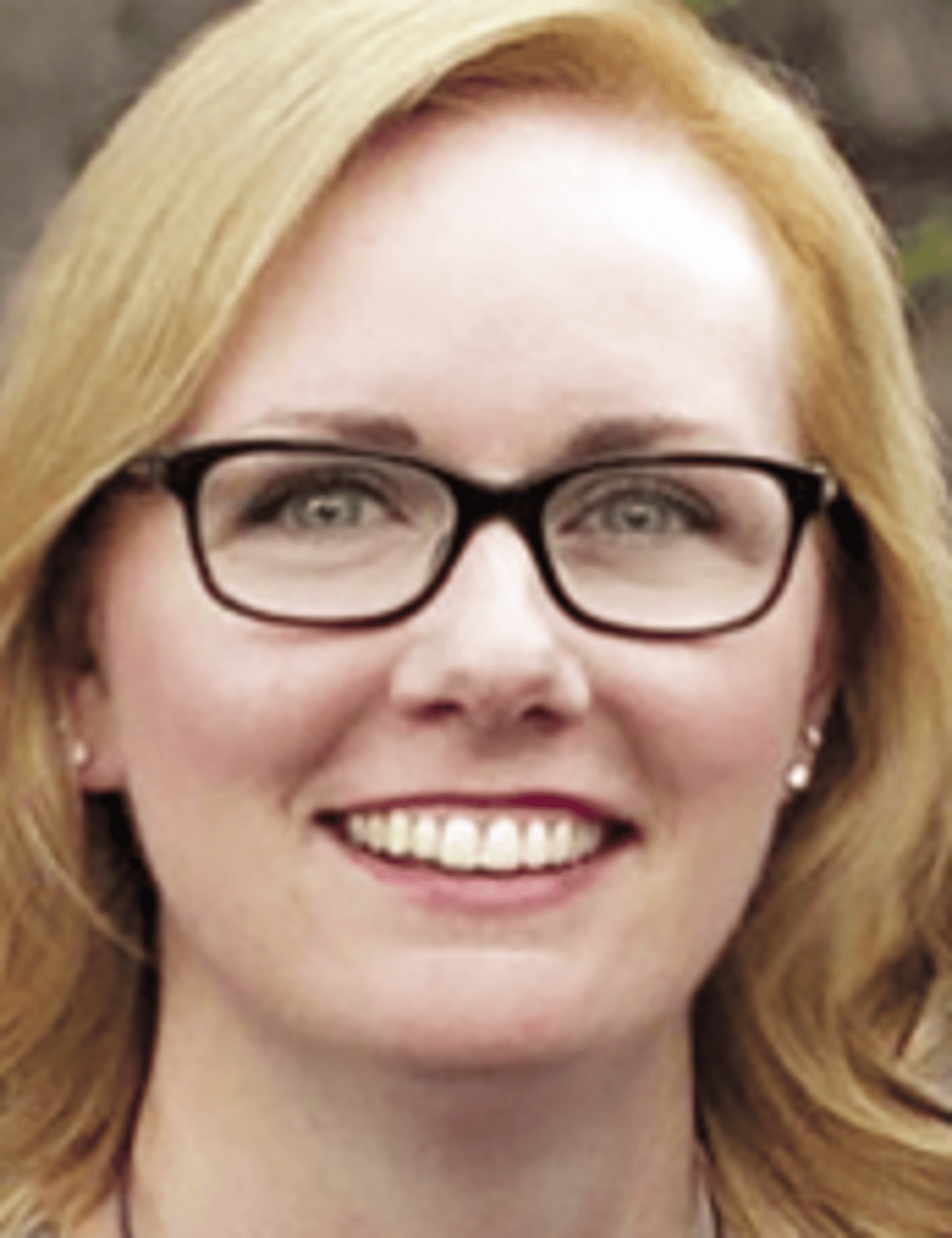 a woman wearing glasses and smiling at the camera