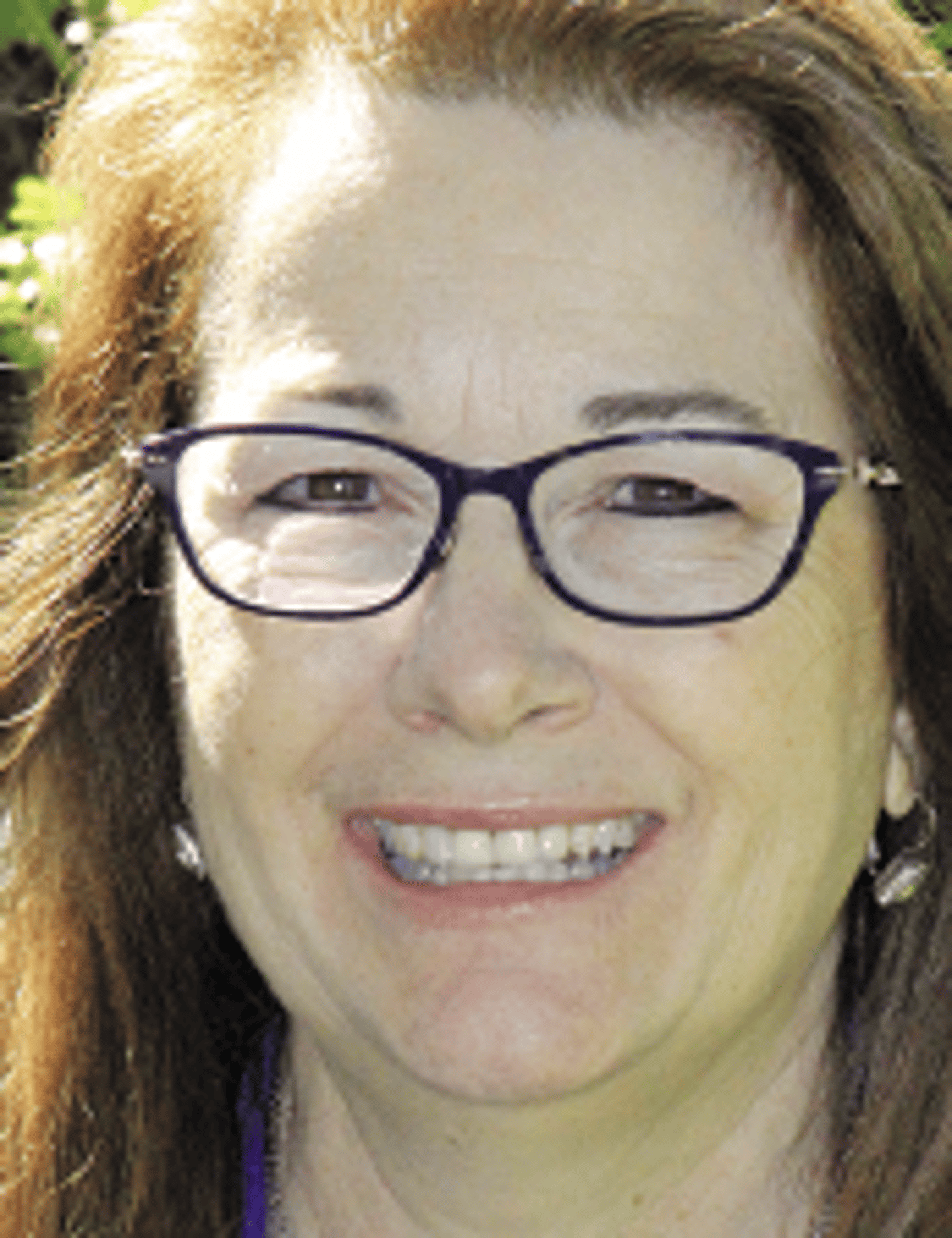 a close up of a woman wearing glasses and smiling at the camera