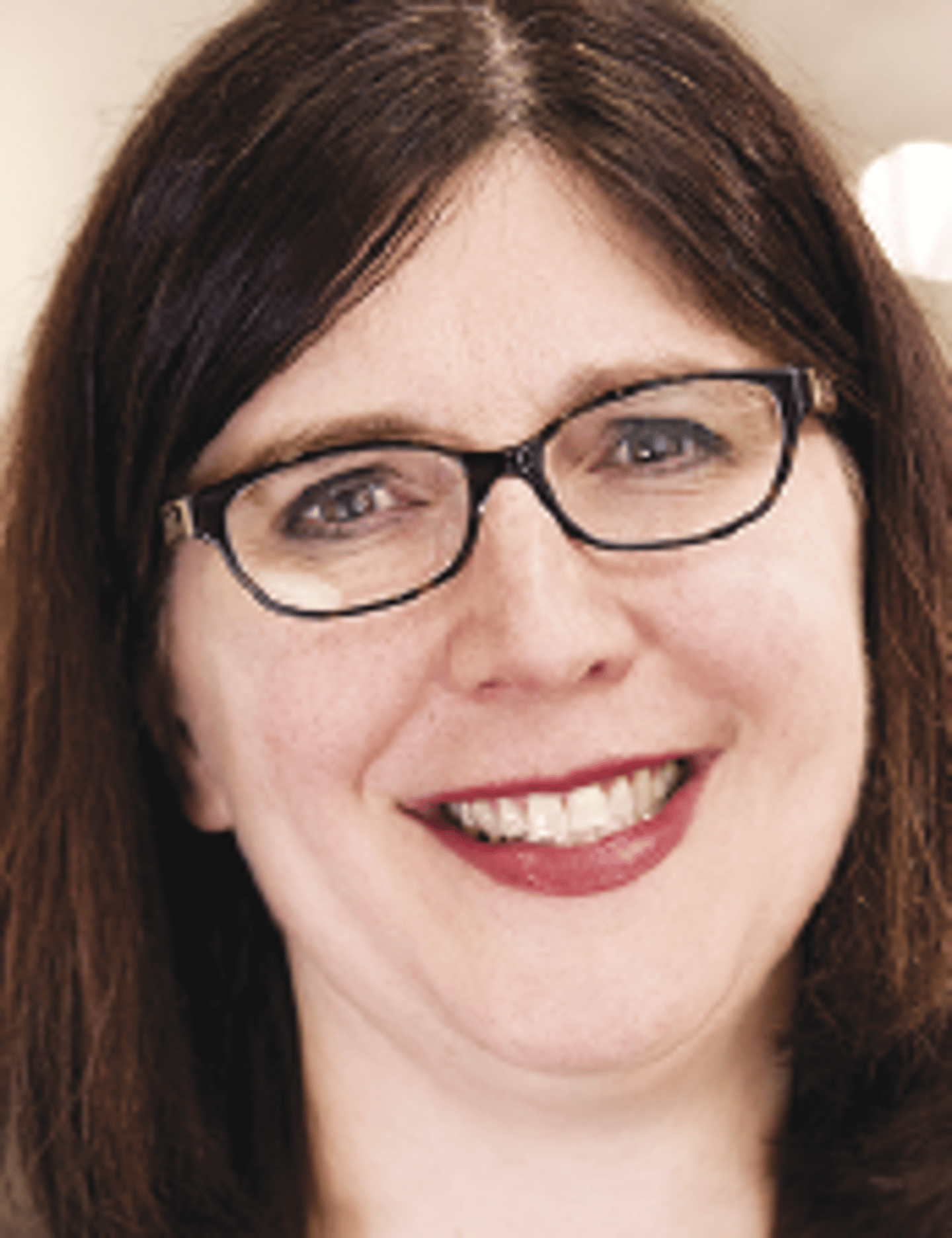 a close up of a woman wearing glasses and smiling at the camera