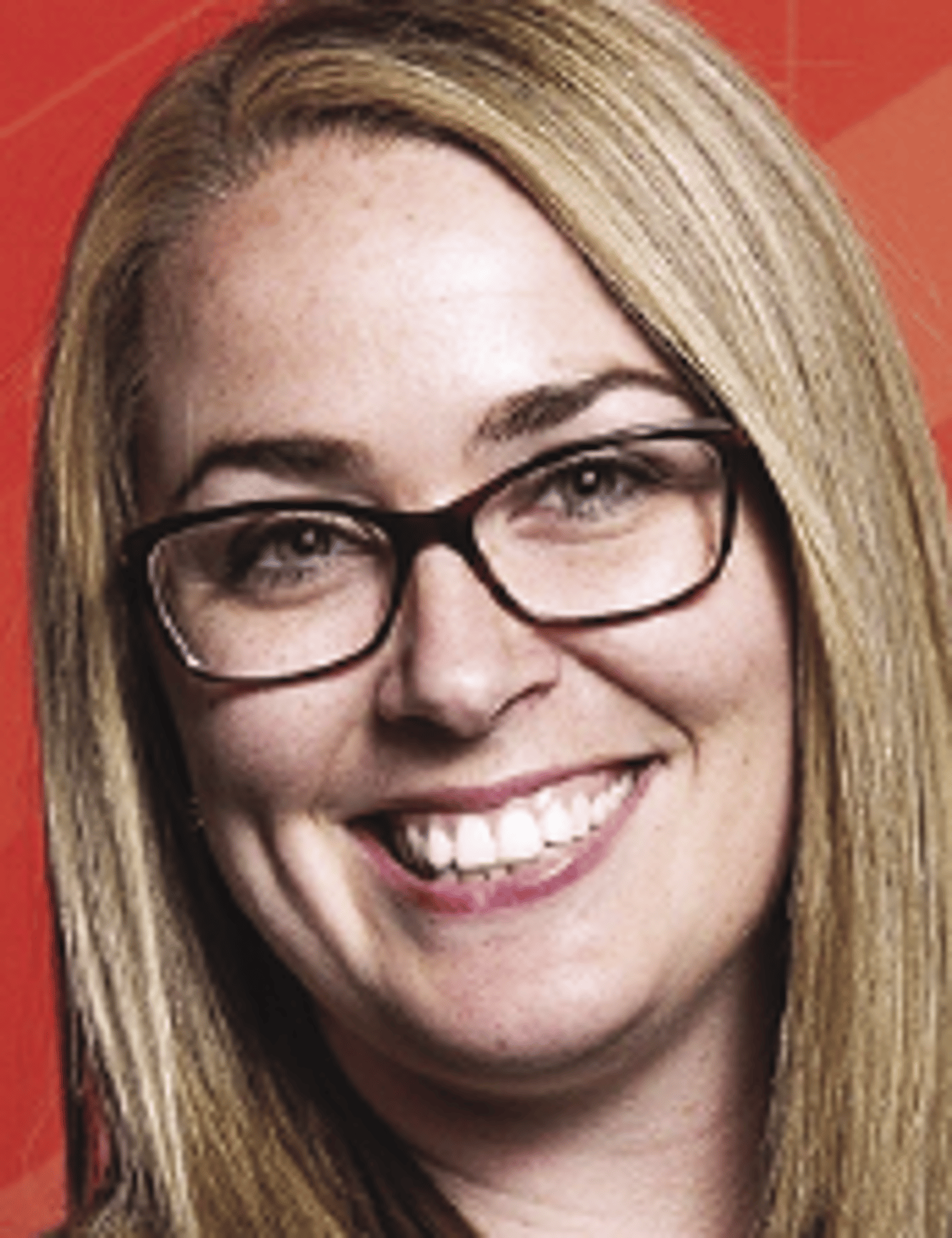 a close up of a person wearing glasses and smiling at the camera