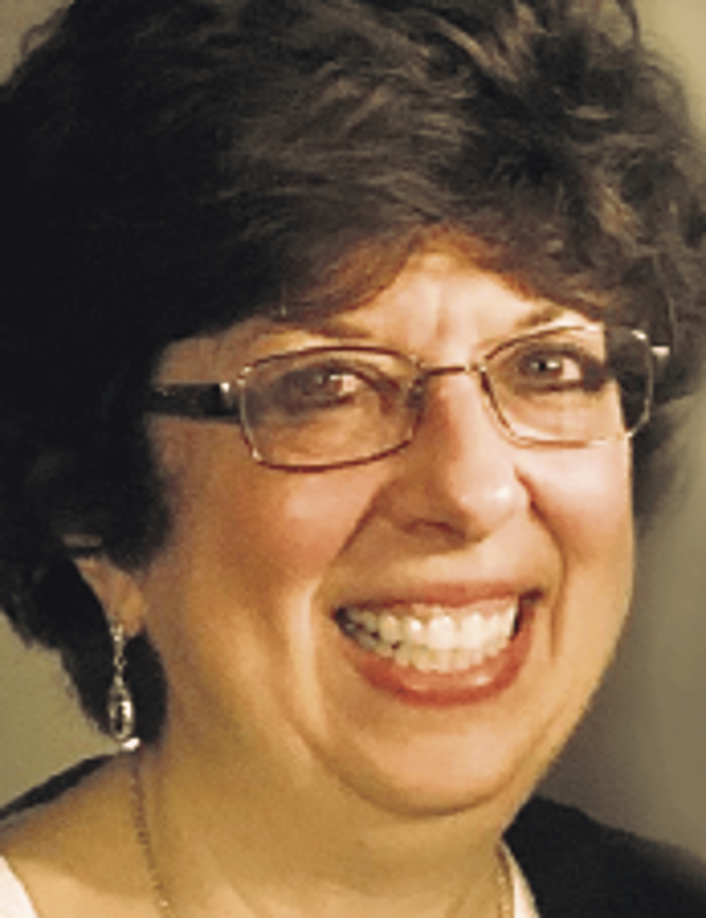 a close up of a woman wearing glasses and smiling at the camera