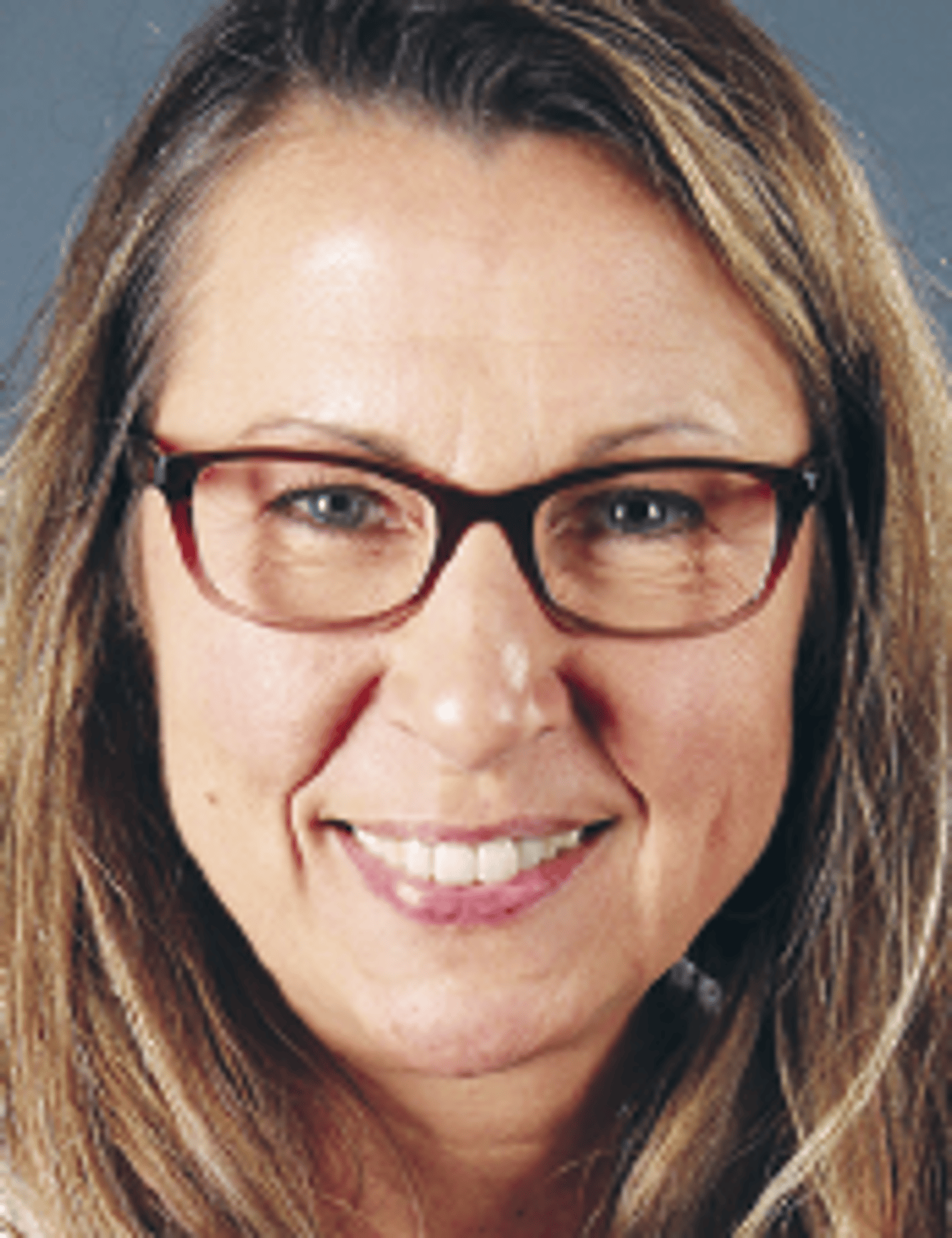 a woman wearing glasses and smiling at the camera