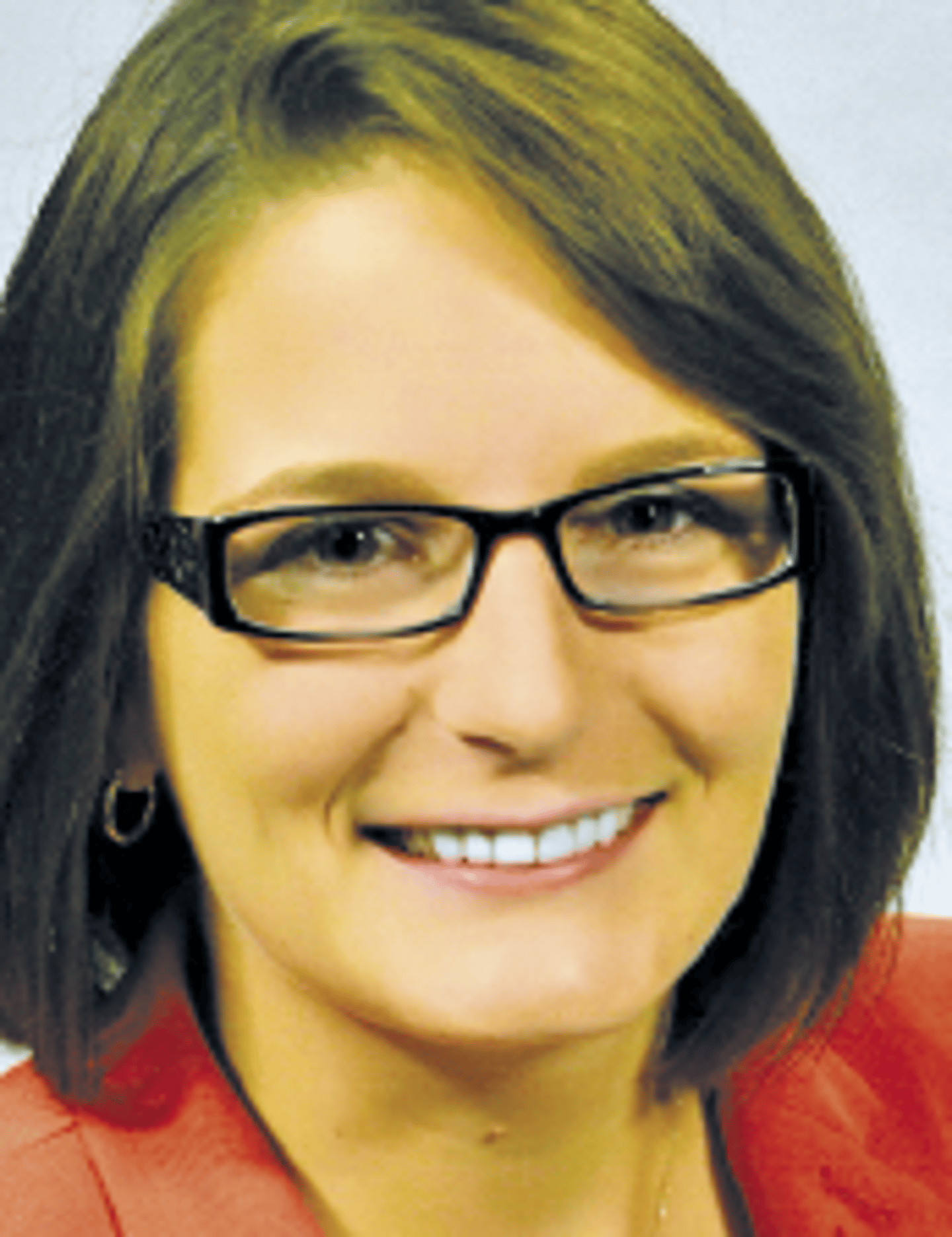 a woman wearing glasses and smiling at the camera