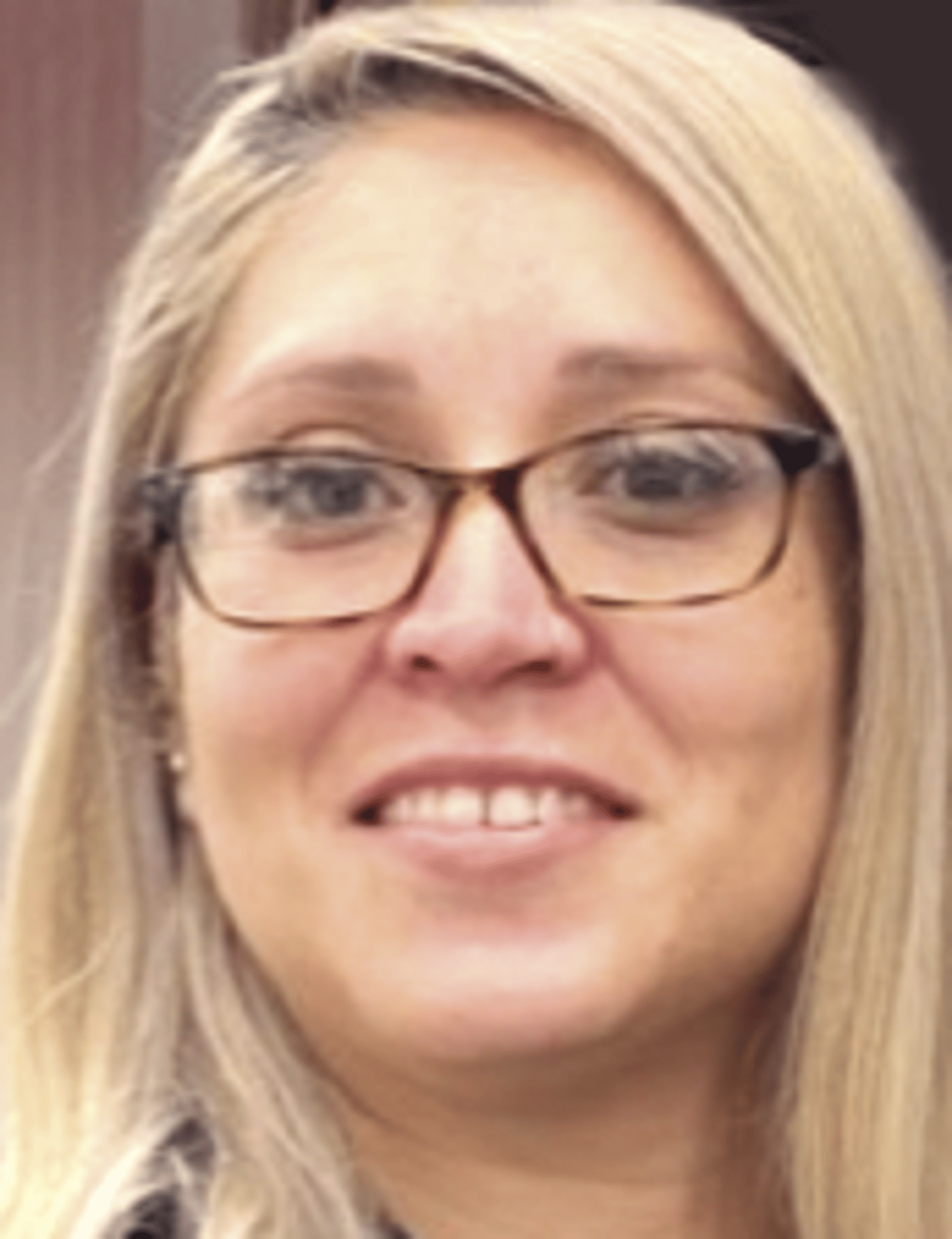 a woman wearing glasses and smiling at the camera