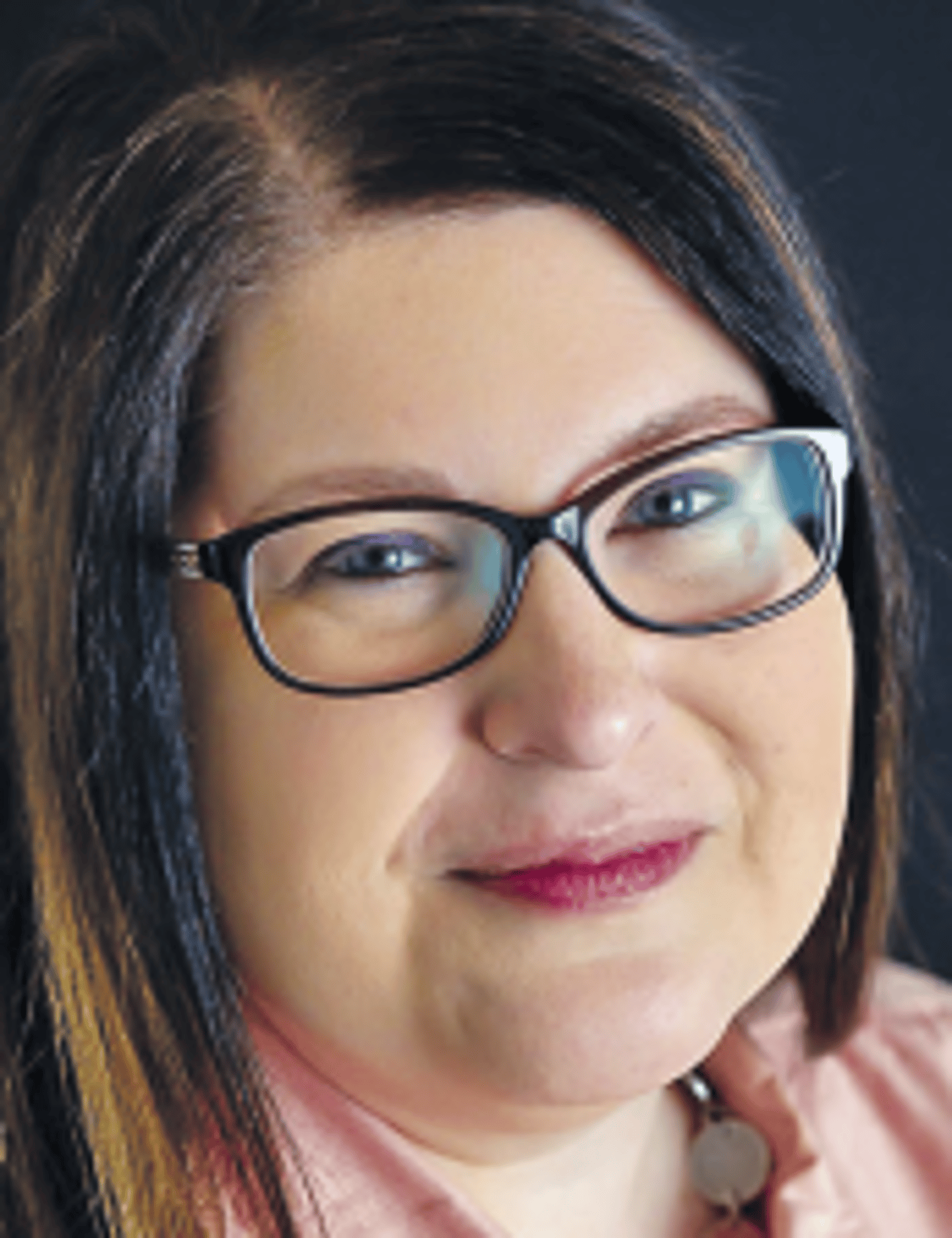 a close up of a woman wearing glasses and smiling at the camera