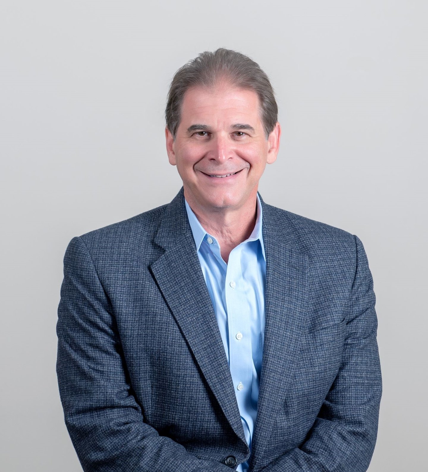 a man wearing a suit and tie smiling at the camera