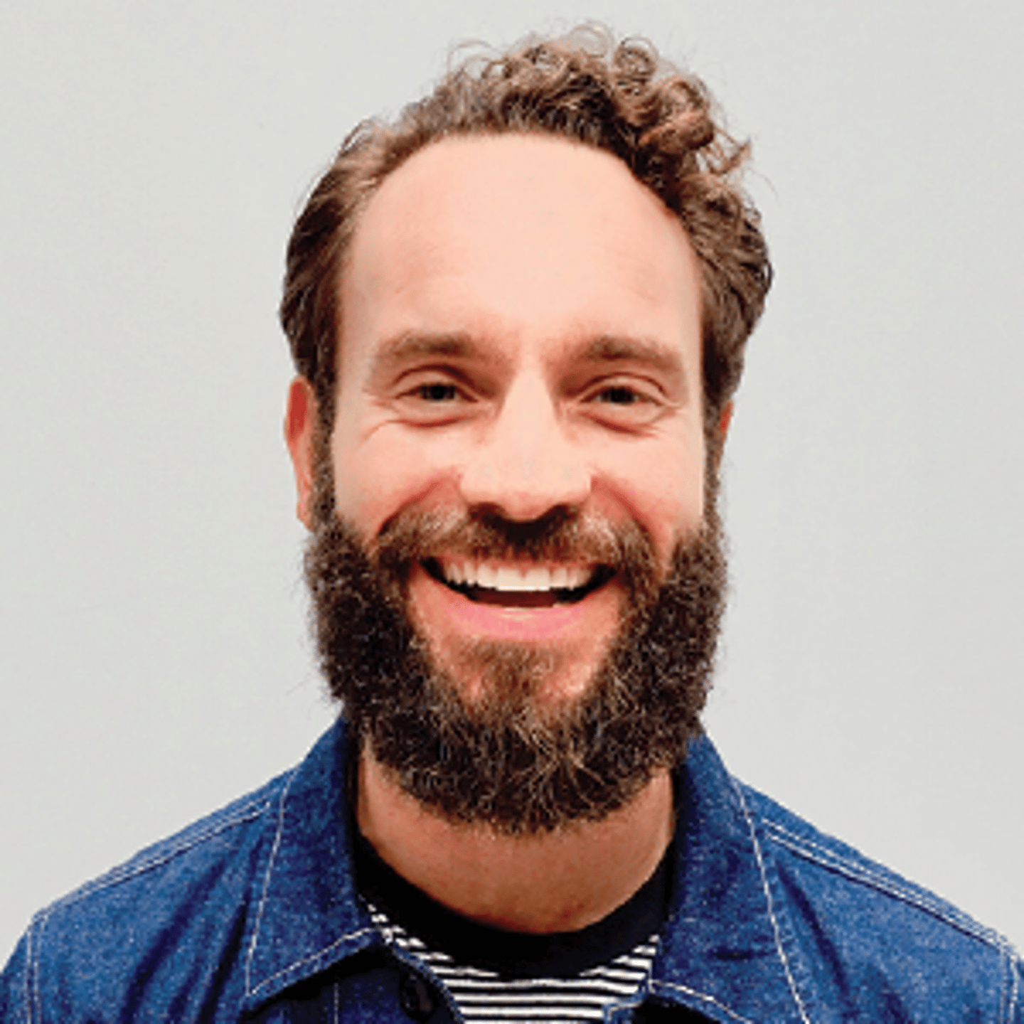 a man wearing a blue shirt and smiling at the camera