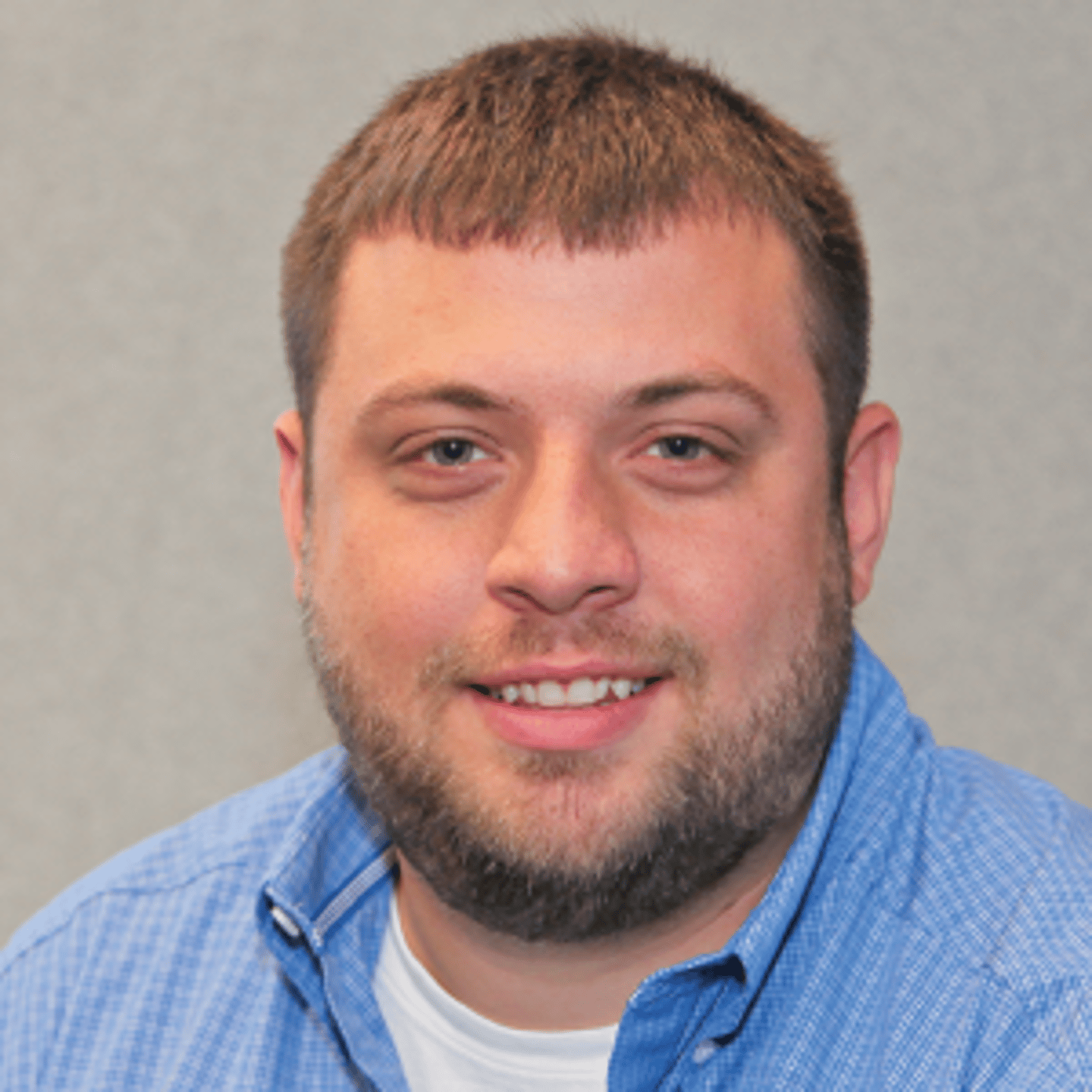 a man wearing a blue shirt and smiling at the camera