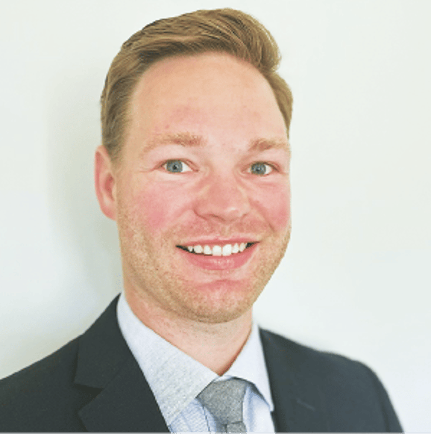 a man wearing a suit and tie smiling at the camera