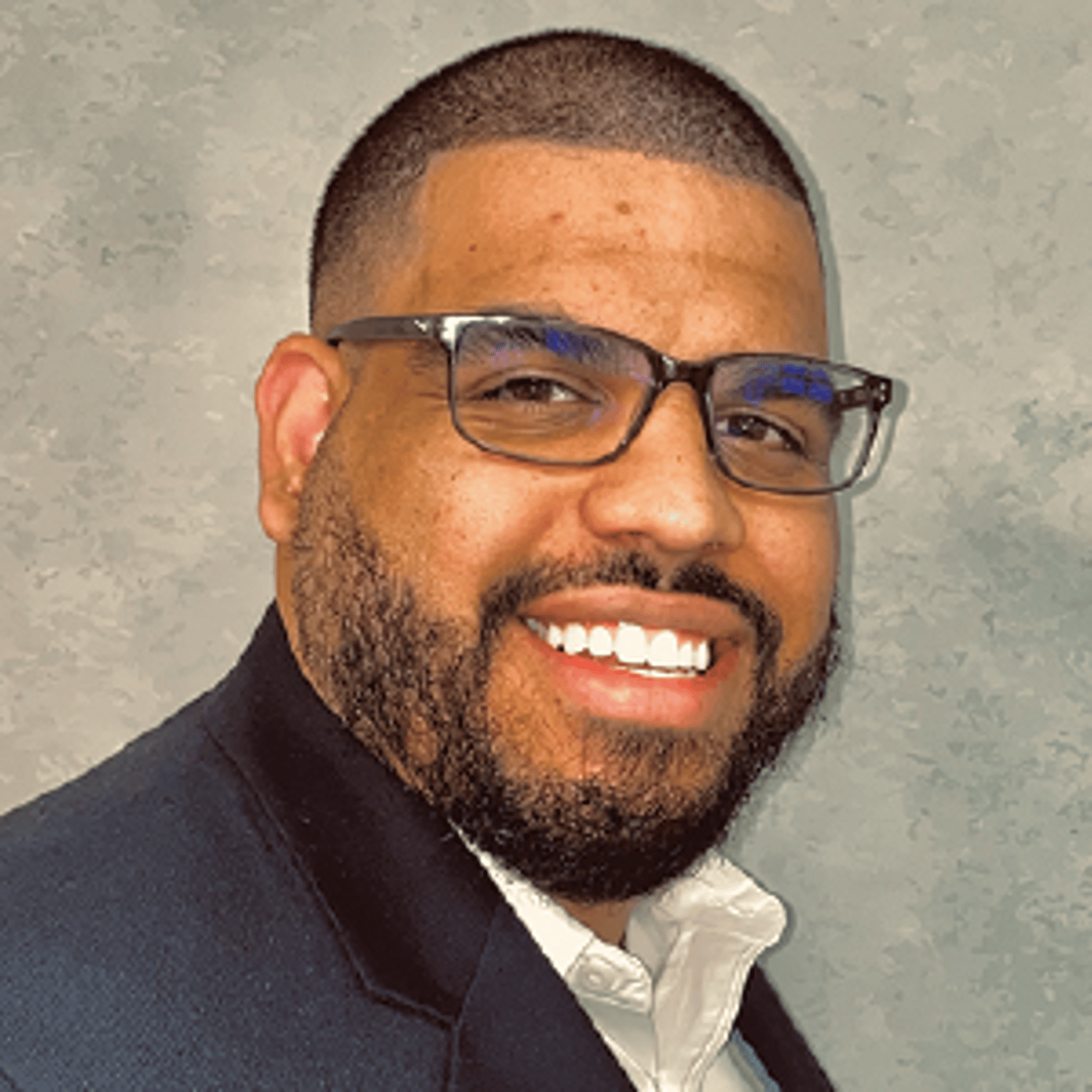 a man wearing glasses and smiling at the camera