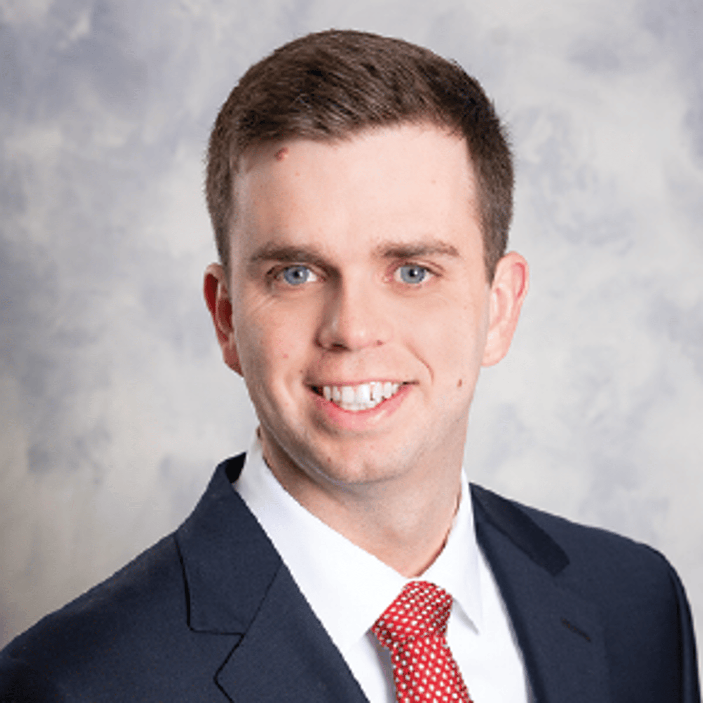 a man wearing a suit and tie smiling at the camera