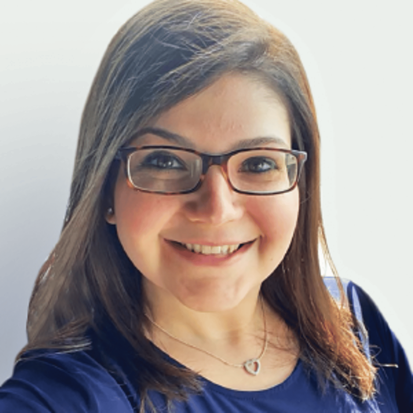 a woman wearing glasses and smiling at the camera