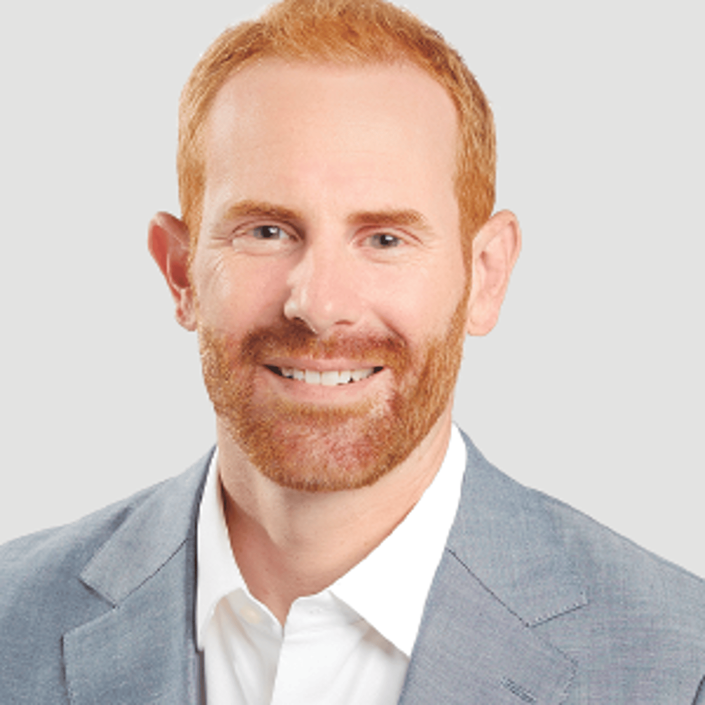 a man wearing a suit and tie smiling at the camera