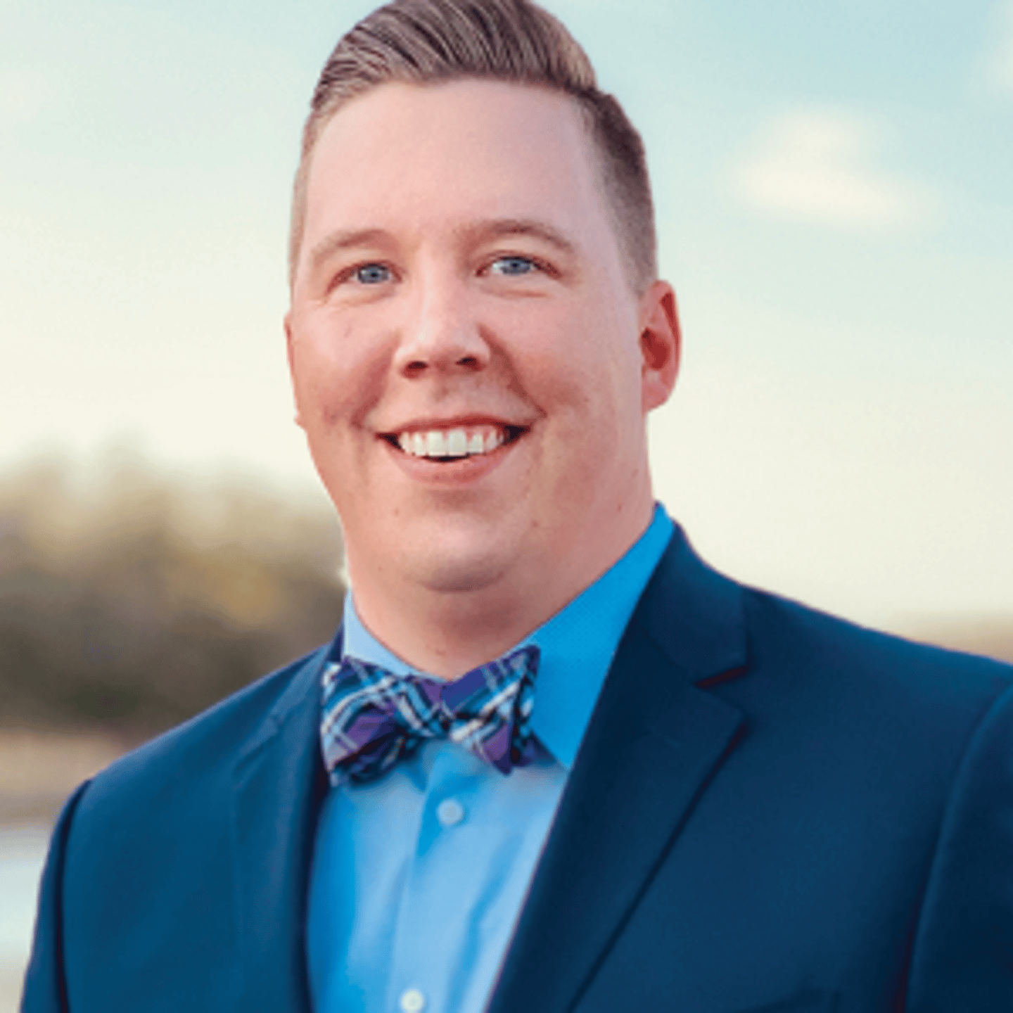 a man wearing a suit and tie smiling at the camera