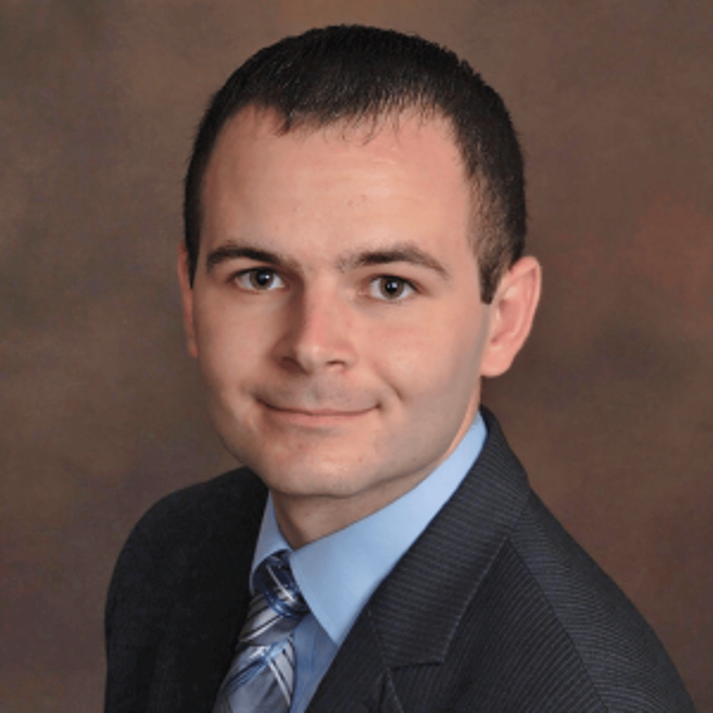 a young man wearing a suit and tie smiling at the camera