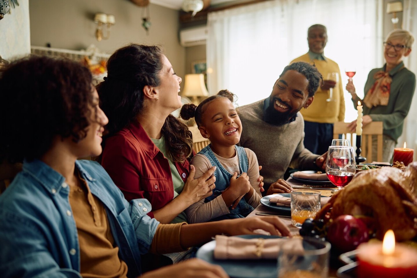 Happy African American girl laughing while enjoying in Thanksgiving dinner with her extended family in dining room.; Shutterstock ID 2372790557