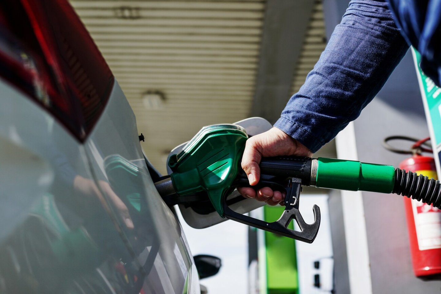 Man driver hand refilling and pumping gasoline oil the car with fuel at he refuel station. Car refueling on petrol station. Fuel pump at station. Refueling the car at a gas station fuel pump.; Shutterstock ID 2450031353